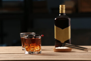 Glasses of delicious Old Fashioned Cocktail with olives on wooden table