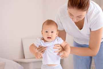 Beautiful young mother with cute little baby in bedroom at home
