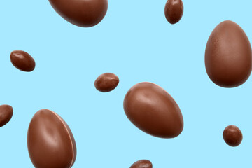 Delicious chocolate eggs flying on blue background