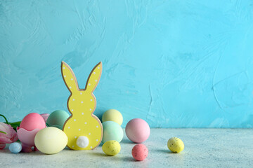 Easter eggs and wooden bunny on grey table near blue wall