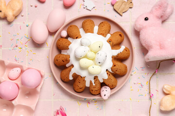 Plate of sweet Easter bread with eggs and rabbits on pink tile background