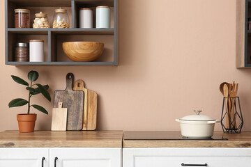 Counters with utensils and shelves on beige wall in kitchen