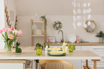 Table setting with Easter rabbits and eggs in kitchen