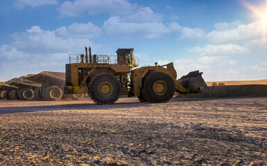 Obraz premium wheel loader at a diamond mine with parked mining trucks at sunset