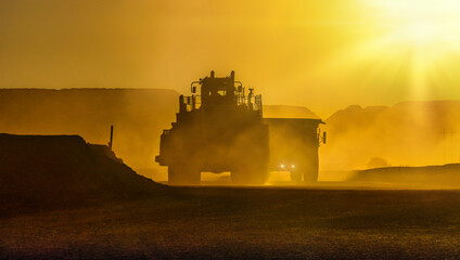 silhouette of truck mining equipment and front loader at a diamond mine ,outdoors sunset with...