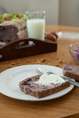 A tender moment captured as a knife lovingly spreads smooth cream cheese on a soft slice of bread, creating a sweet and intimate snack that invites warmth and comfort.

