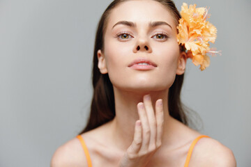 A young woman with a flower in her hair, showcasing natural beauty and confidence in a soft pastel...