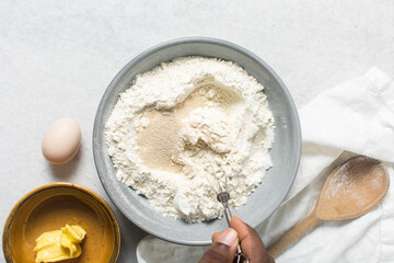 Overhead view of doughnut dough being mixed in a grey mixing bowl, top view of doughnut dough on a white countertop, process of making doughnut
