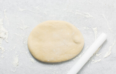 Overhead view of doughnut dough being rolled on a white countertop, top view of doughnut dough on a white countertop, process of making doughnut