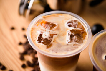Iced latte in plastic cup on wooden table
