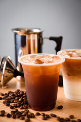 Iced coffee in plastic cup on wooden table with coffee beans
