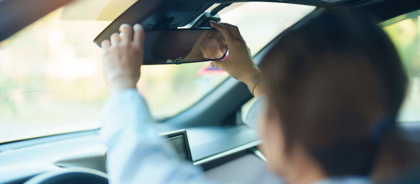 Business woman driver adjusting rear view mirror a car. Journey, trip and safety Transportation concepts - Powered by Adobe