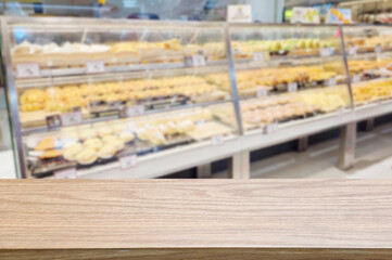 A wooden tabletop in the foreground with a blurred view of a bakery display in the background, ideal for product placement or advertising