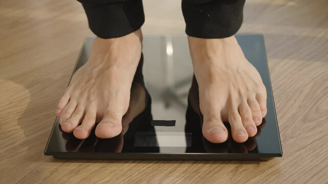 Close-Up of Barefoot Person Standing on Black Digital Scale with Measurement Display