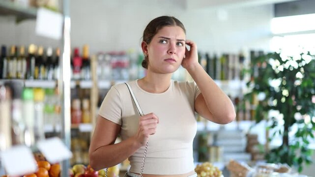  Young woman buyer forgot what she wanted to buy at grocery store