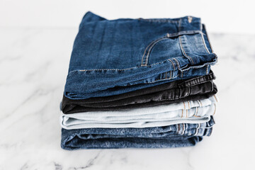 pile of jeans in different color denim fabric neatly folded and piled up