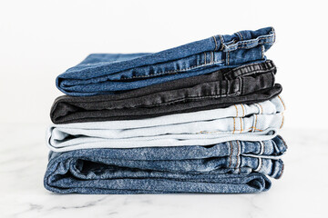 pile of jeans in different color denim fabric neatly folded and piled up