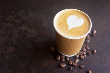 hot latte coffee in takeaway paper coffee cup, ready to go coffee on brow rustic table.