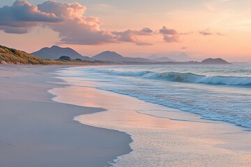 Fototapeta premium A tranquil beach scene with mountains and pink sunset clouds
