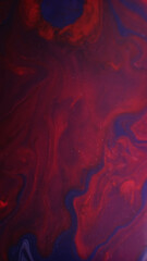 Paint flow. Mix color. Defocused red maroon purple marble liquid chemical texture acrylic bubble fluid on abstract dark black background.