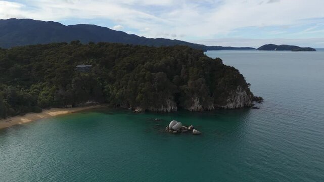 Aerial establishing of Split Apple Rock in Tasman Bay, surrounded by blue ocean and lush green coastline