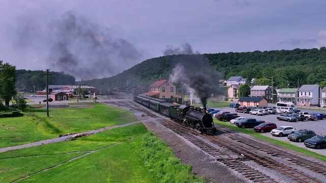 A classic steam train departs from a quaint town, moving along picturesque tracks surrounded by lush greenery and rolling hills.