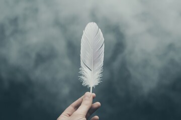 Sensitive person holding a feather in a misty environment for artistic inspiration