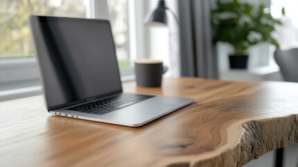 Fototapeta premium A bright, organized workspace with a sleek laptop, coffee cup, and lush green plants adds an invigorating touch of nature to the modern setting.