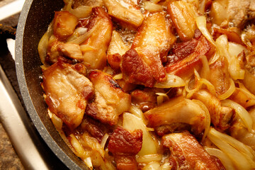 A pan of meat and onions is cooking on a stove