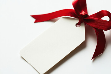 A blank gift tag tied with red ribbon on a white background