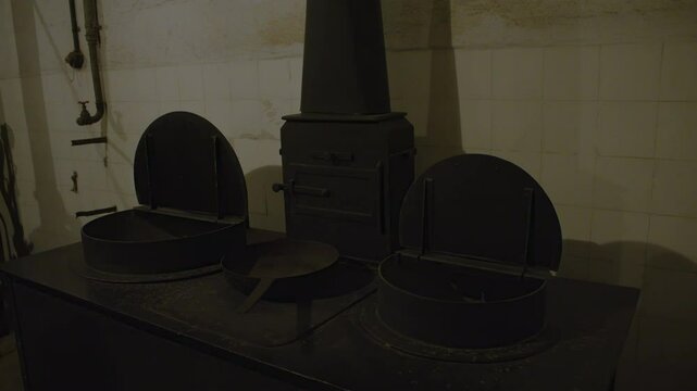 A black cast iron stove with two round openings on either side and a tall, cylindrical oven in the center. 