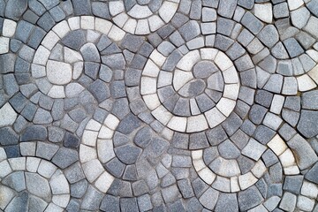 Intricate stone pavement with spiral patterns in various shades of gray.