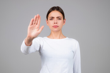 Woman with stop gesture. Young woman doing stop sign with palm of the hand. Portrait of young woman extending one hand, stop taboo sign, rejecting, declining. Girl showing stop gesture.