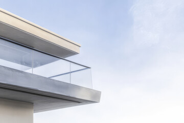 Modern architecture featuring a sleek balcony with glass railings against a cloudy sky