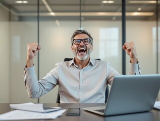 Happy businessman with glasses raising fists in excitement at office desk with laptop, papers, and phone, expressing achievement. Ai generative