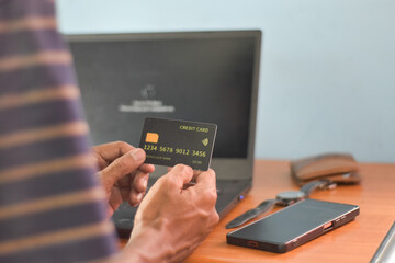 A person holding a fake credit card against a work desk background