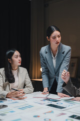 Businesswomen working late analyzing financial charts and graphs in office meeting