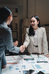 Businesswomen shaking hands after successful meeting in office at night