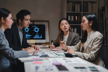 Asian business team working late analyzing financial charts on a desktop computer