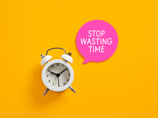 White alarm clock showing eight o'clock next to pink speech bubble saying stop wasting time on...