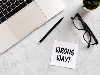 Wrong Way message on sticky note with laptop, glasses and pen on desk