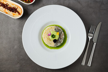 Gourmet shrimp and white fish tartare with avocado mousse, edible flowers, and green sauce, served on a white plate