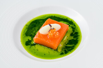 Sous-vide salmon fillet with fish roe, garnished with sorbet and microgreens, served on a vibrant green herb sauce