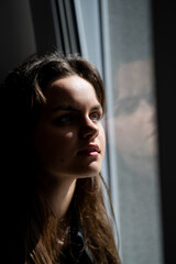 Fototapeta premium Close up portrait of dreaming girl. Teem imagining near window. Little dreamer. Imaginative girl. Dreamy teenager looking up. Teen face. Teenager girl with a dreamy expression. Thoughtful teen.