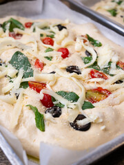 Raw Focaccia with olive tomatoes and rosemary. Homemade Italian Sourdough Bread on white cafe table.