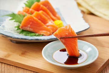 醤油をつけた新鮮なサーモンの刺身