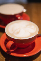 Two red cups filled with coffee served on wooden table