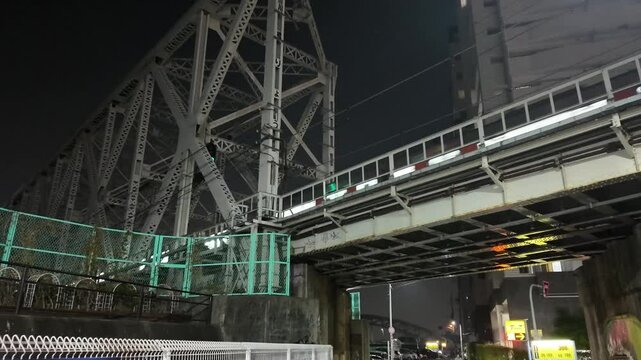 大阪府大阪市大正区、大正駅に電車が乗り入れる夜の風景。架道橋から捉えたダークでムーディーな都市の夜景。