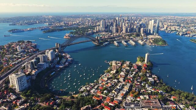 Drone video from above north Sydney facing the CBD with lavender bay, the opera house and harbour bridge. Drone flies slowly toward the west revealing more of surrounding harbour and suburbs