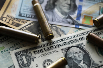 Illegal selling, criminal money concept, US dollars and bullet for a gun, cartridges on a background